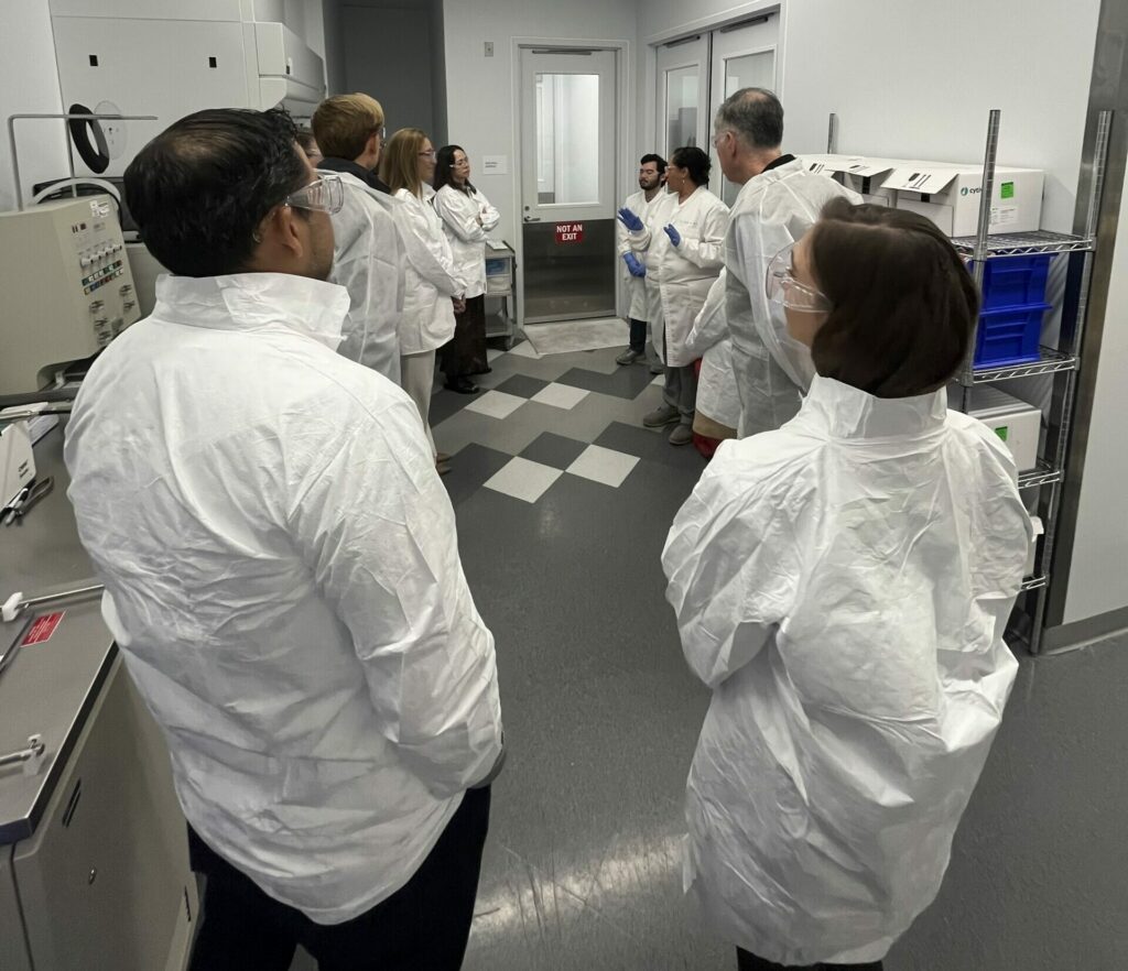 Cell and gene therapy cleanroom facility tour with scientists in protective equipment demonstrating advanced manufacturing protocols