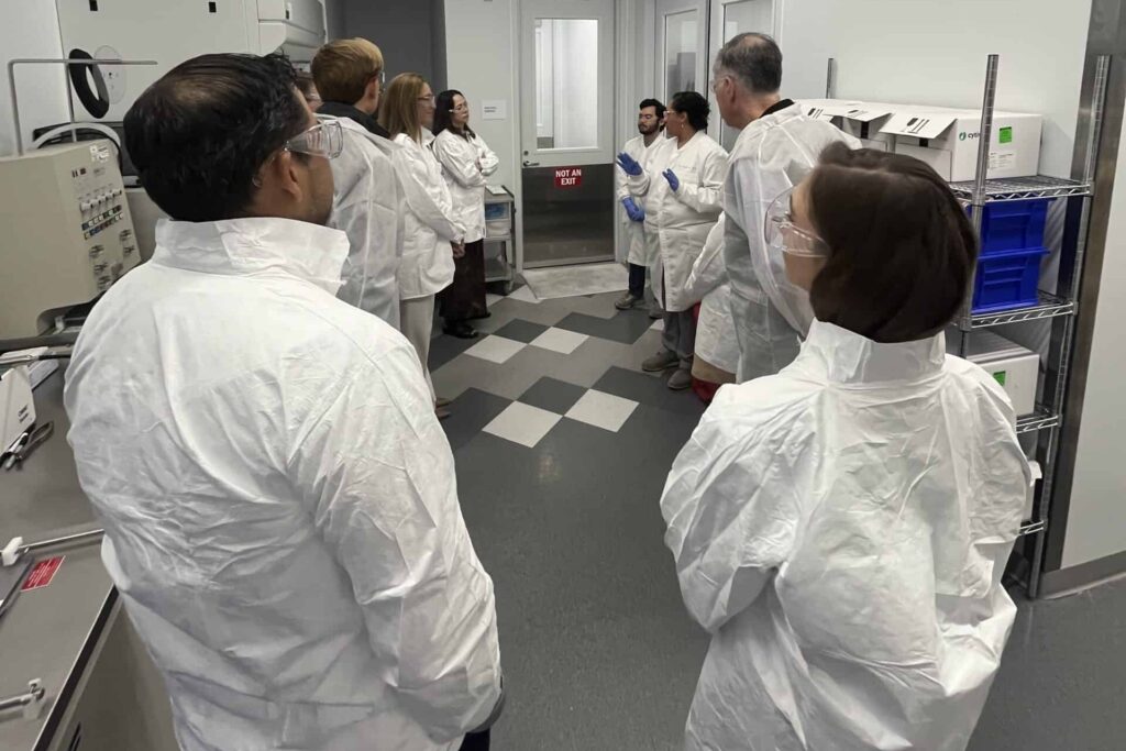 Cell and gene therapy cleanroom facility tour with scientists in protective equipment demonstrating advanced manufacturing protocols