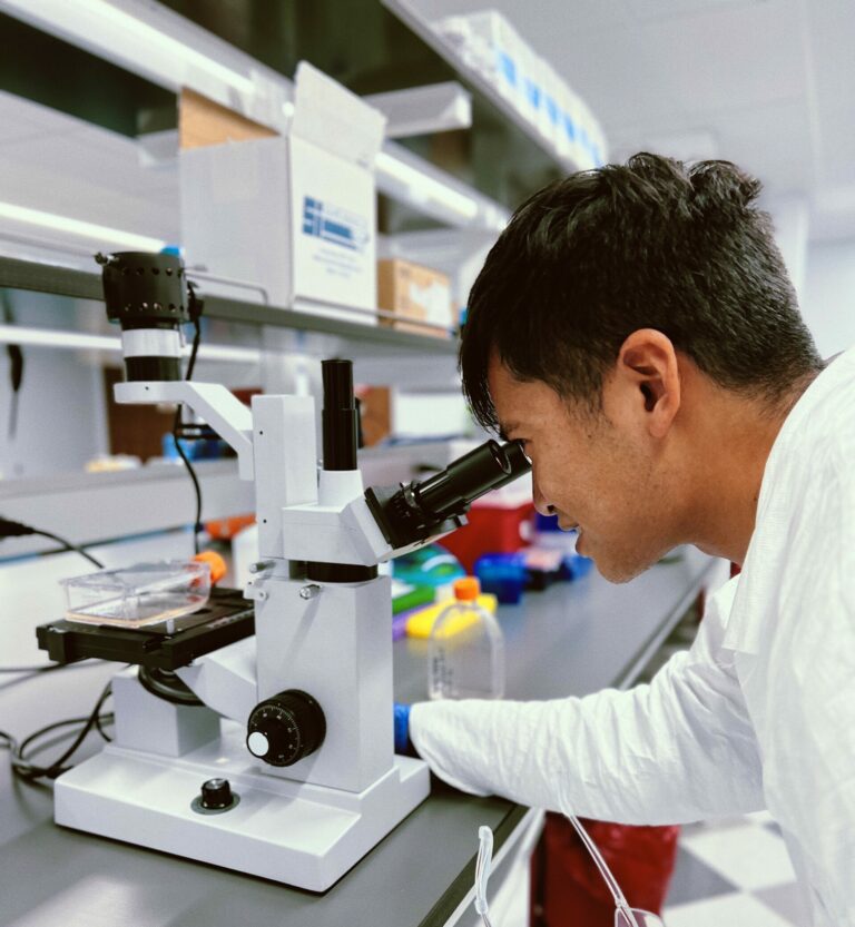 Excellos Process Development scientist analyzing cell samples through microscope in GMP laboratory for cell therapy development